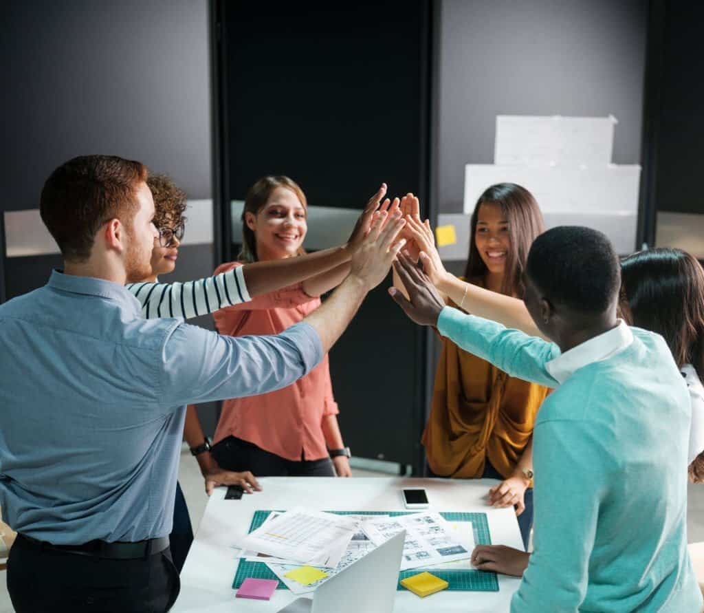 Business team cheerfully giving one another high five
